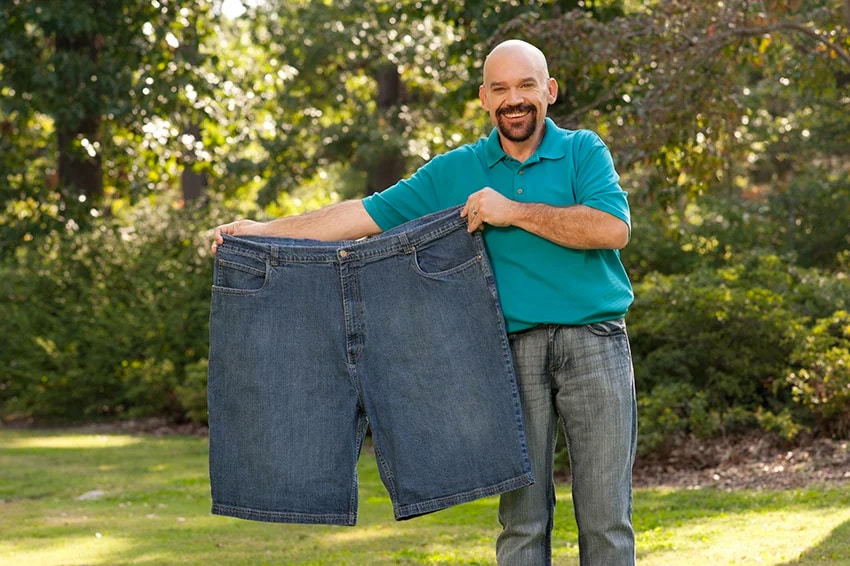 man holding extremely large pair of shorts next to him